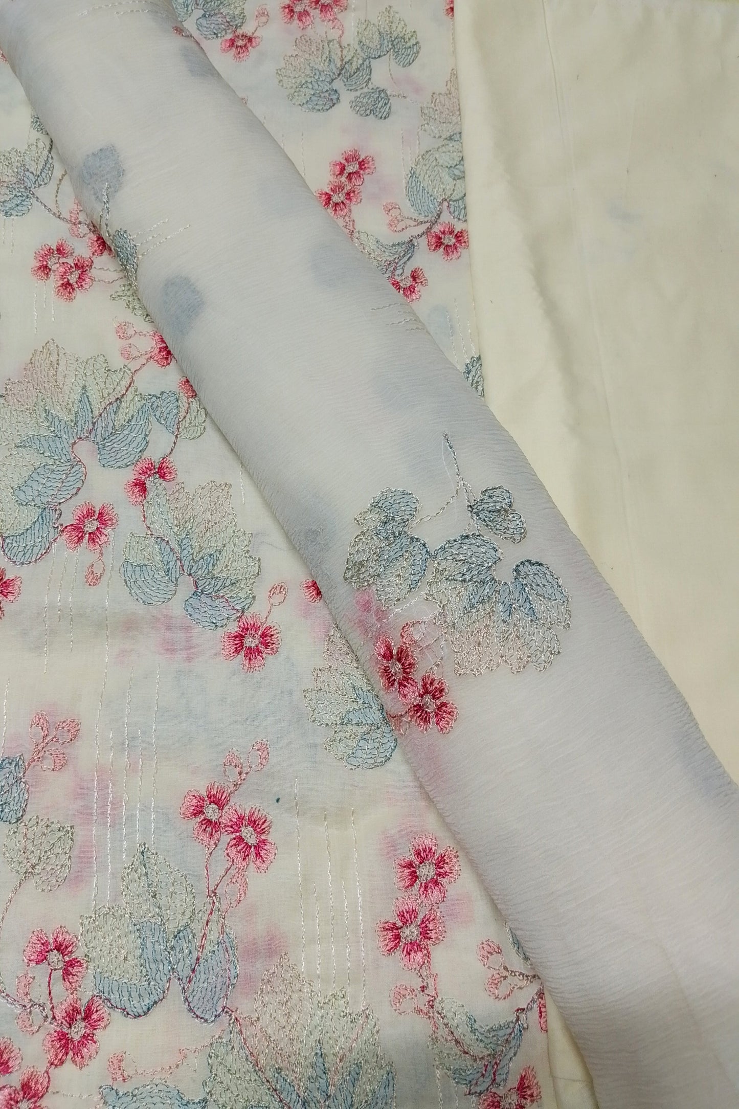 Floral-patterned fabric with pink and blue flowers on a white background