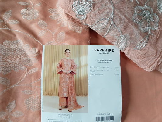 Pink fabric with silver floral embroidery and a pattern book on top