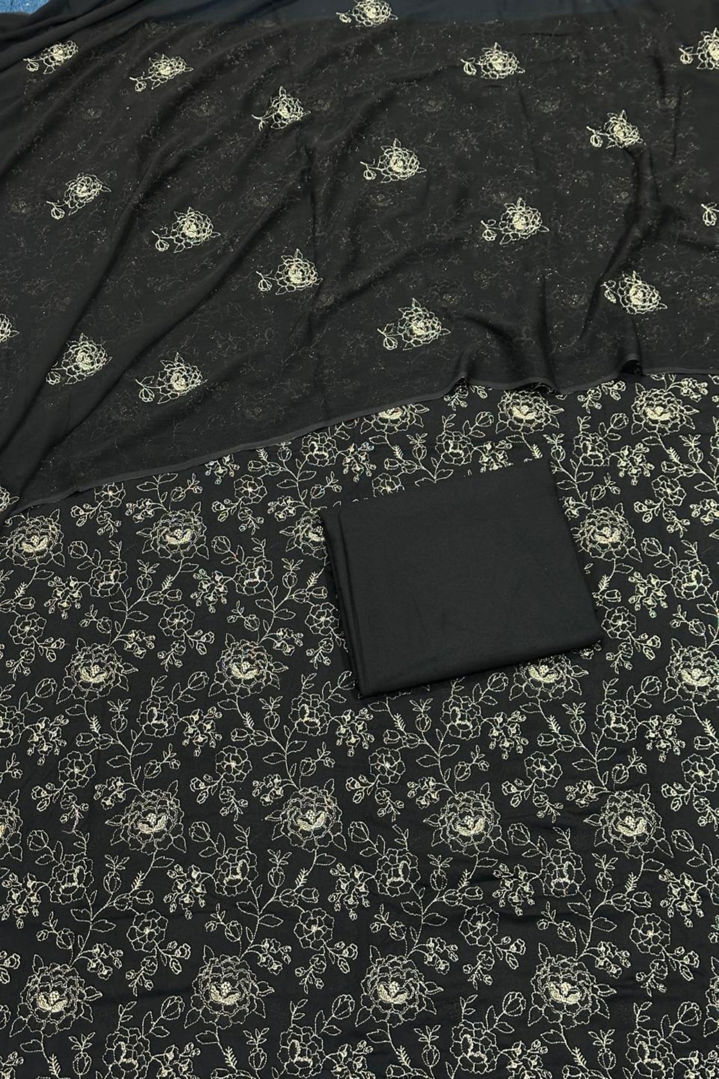 Black fabric with floral pattern and a black wallet on top