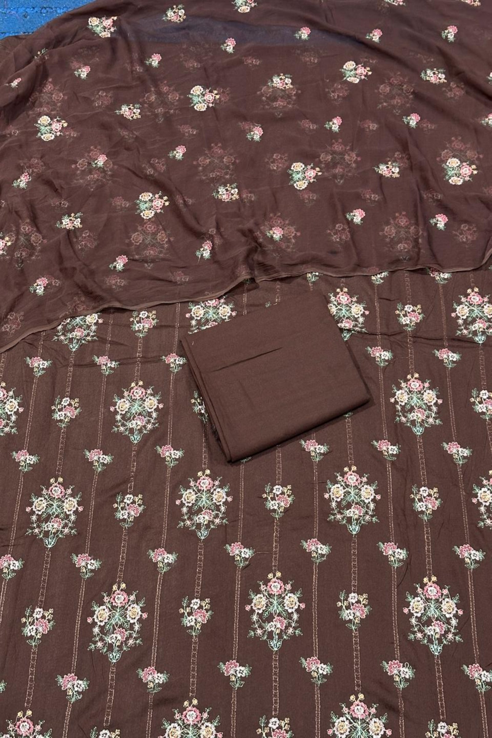 Brown fabric with floral pattern and a folded brown square on top