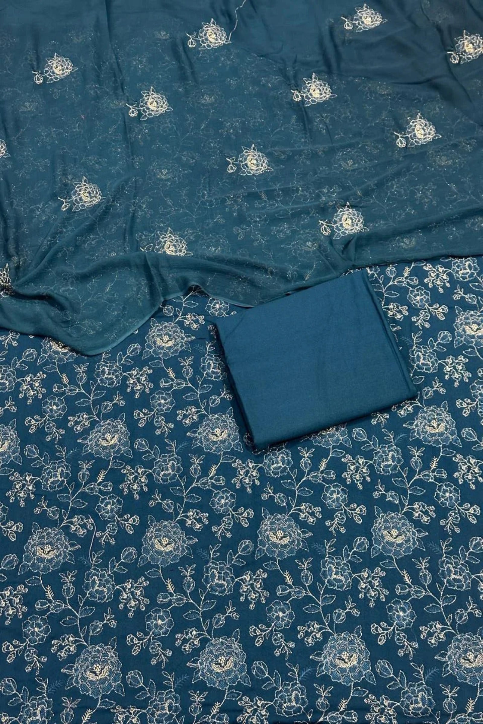 Blue fabric with white floral patterns on a matching blue background