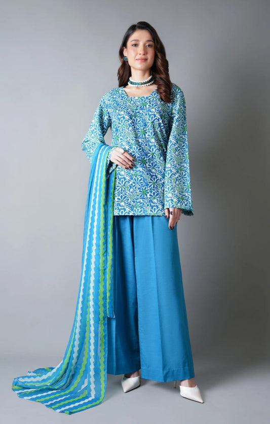 Woman wearing a blue and green traditional outfit with a matching dupatta on a gray background