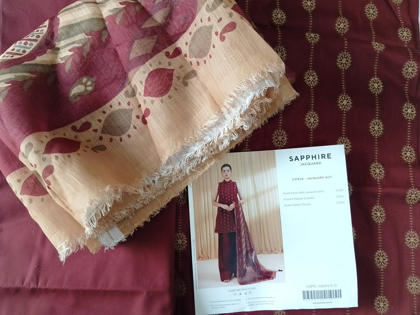 Folded fabric with a pattern on a red fabric background, accompanied by a magazine or catalog page.
