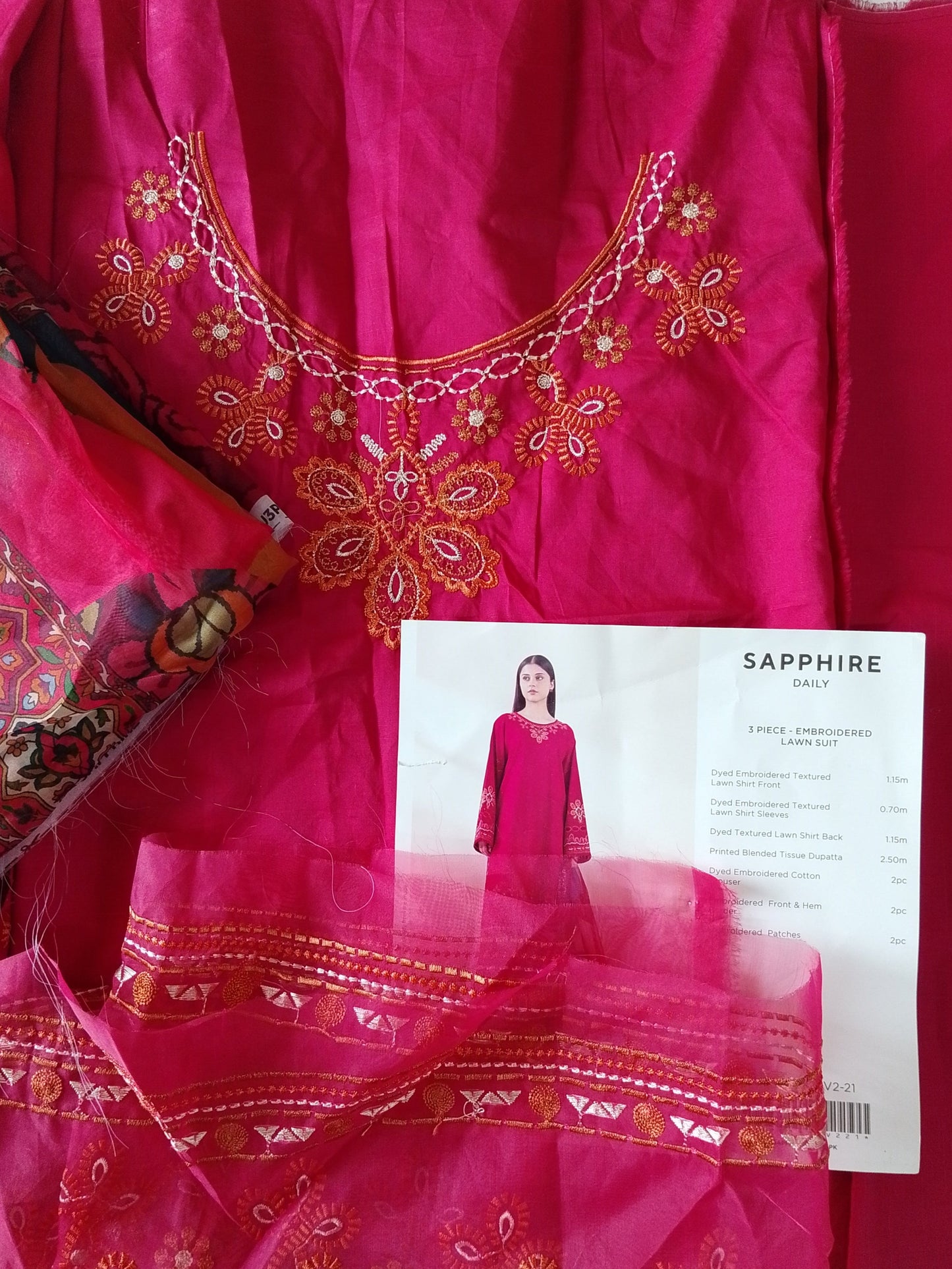 Pink embroidered fabric with a pattern and a paper with text on a red background