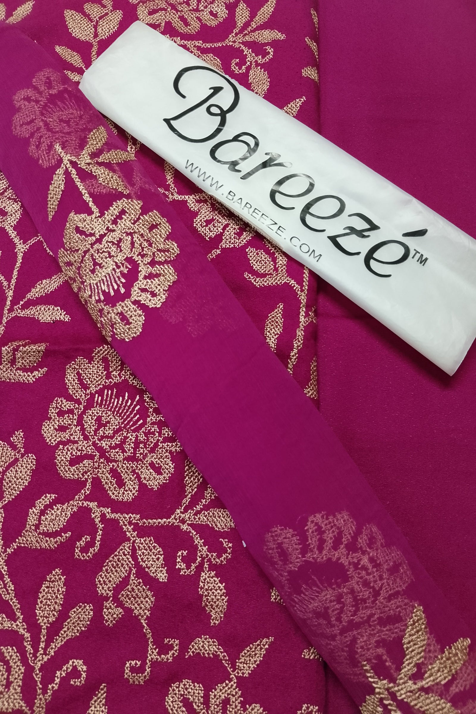 Pink fabric with gold floral patterns and a Barveze label on top.