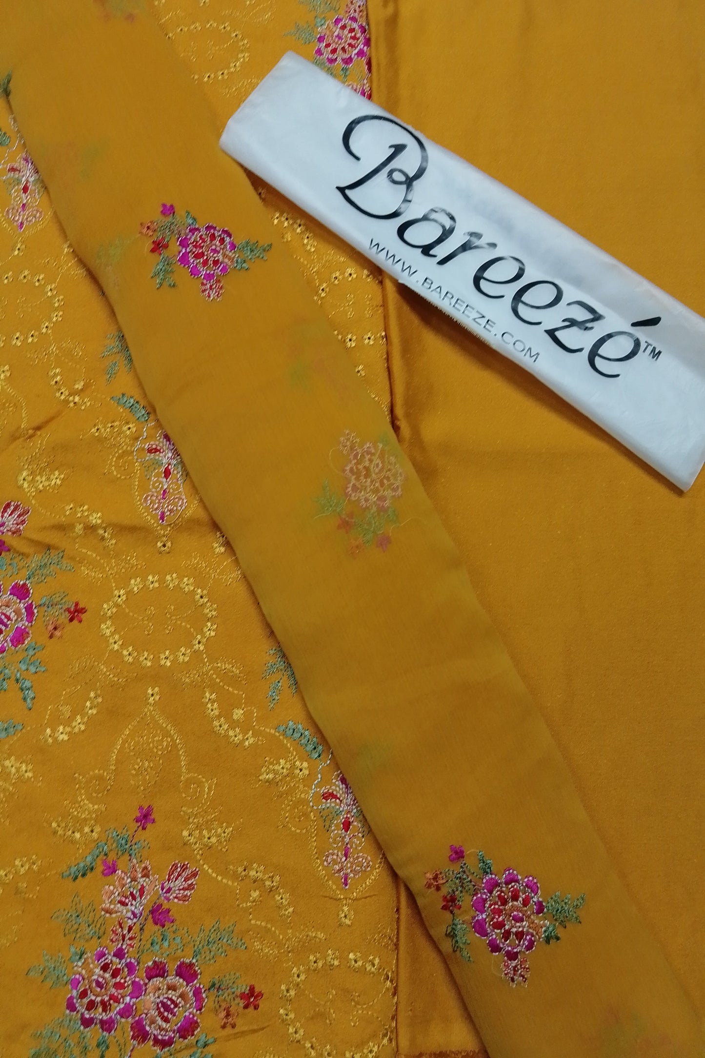 Yellow fabric with floral patterns and a Bareeze label on a yellow background