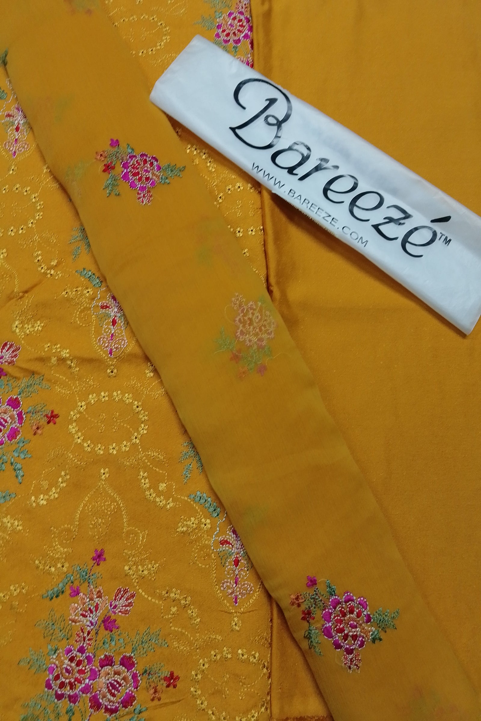 Yellow fabric with floral patterns and a Bareeze label on a yellow background