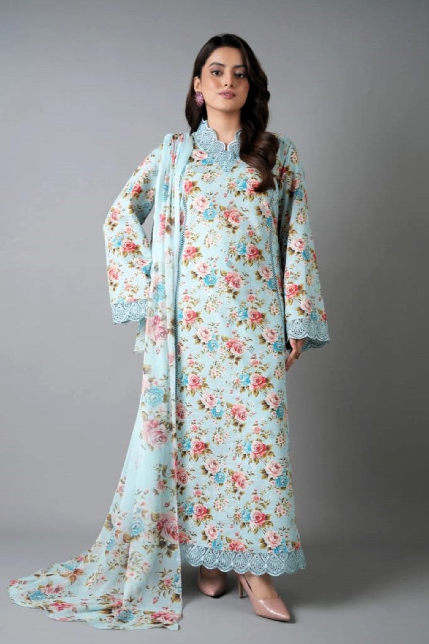 Woman wearing a floral dress with a matching dupatta against a gray background