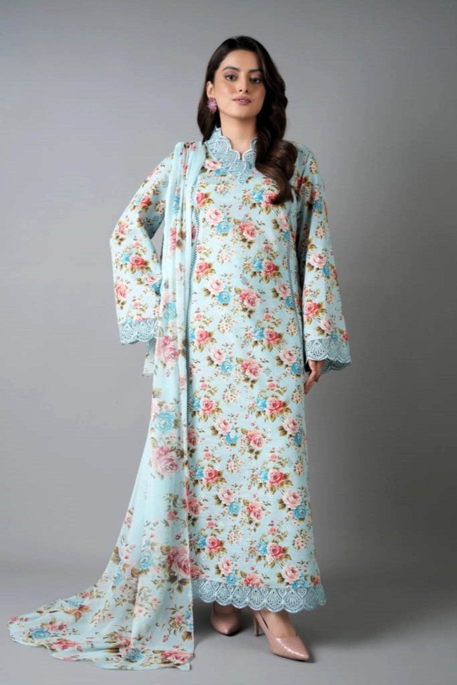 Woman wearing a floral dress with a matching dupatta against a gray background