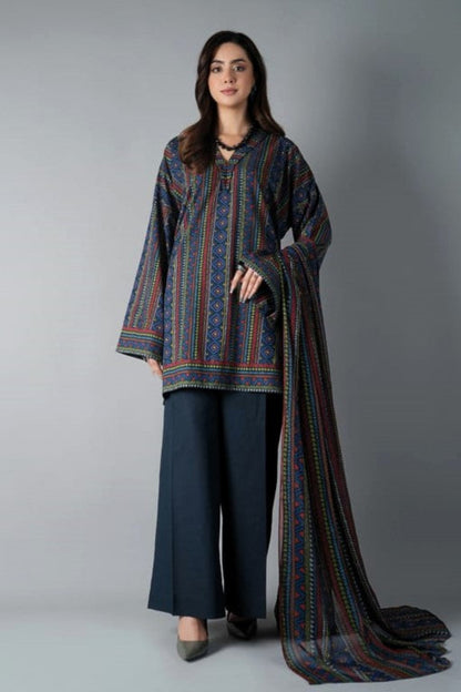 Woman wearing a patterned outfit with a long scarf against a gray background