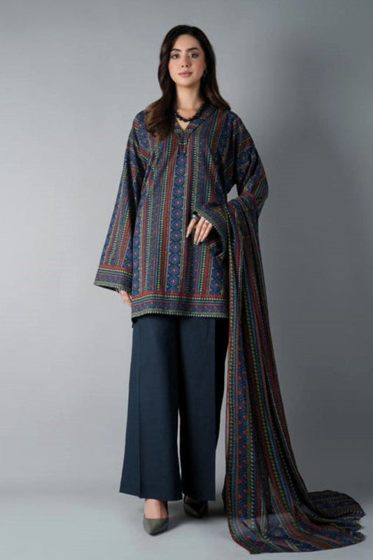 Woman wearing a patterned outfit with a long scarf against a gray background