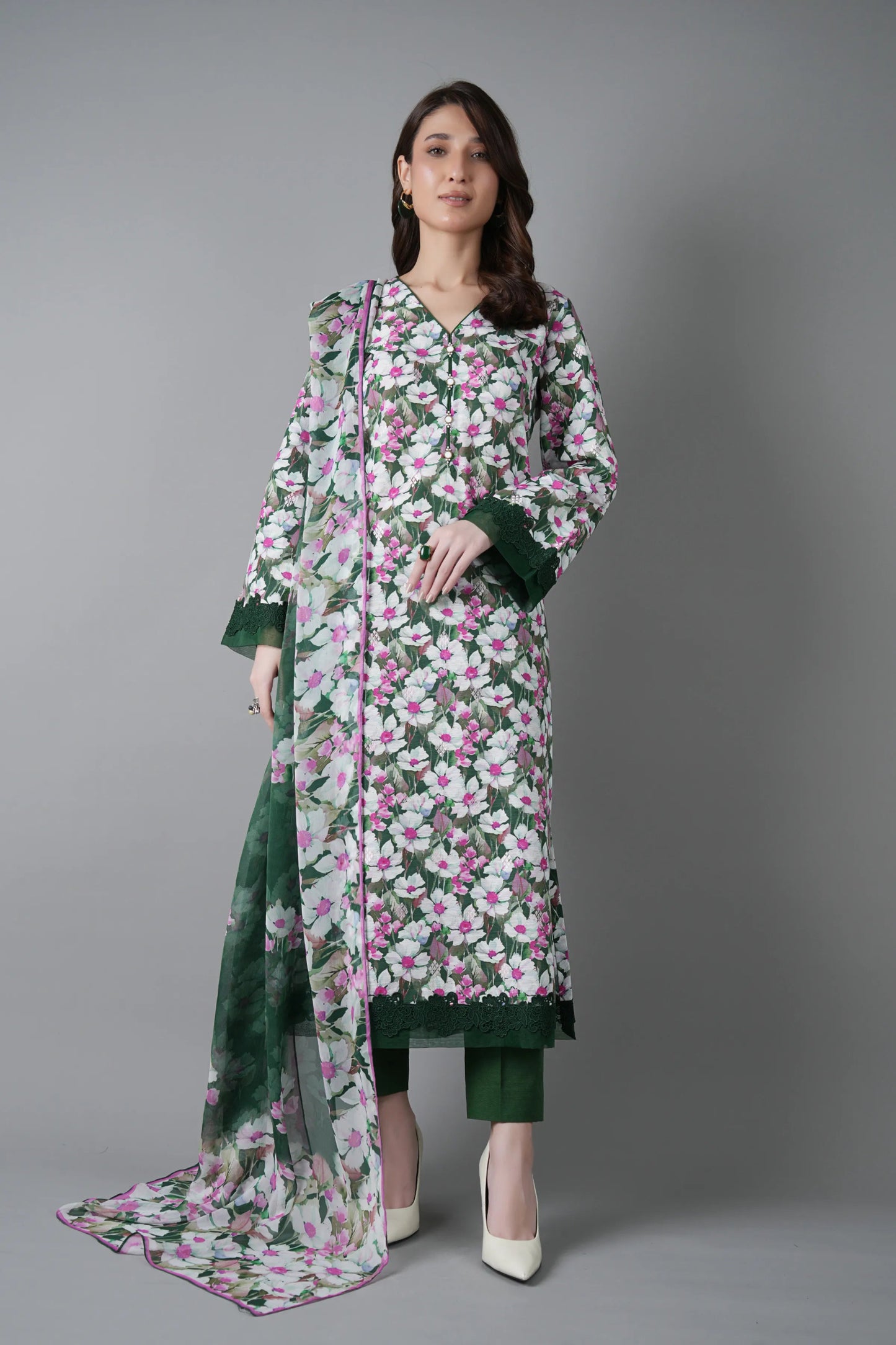 Woman wearing a floral dress with a green dupatta on a gray background
