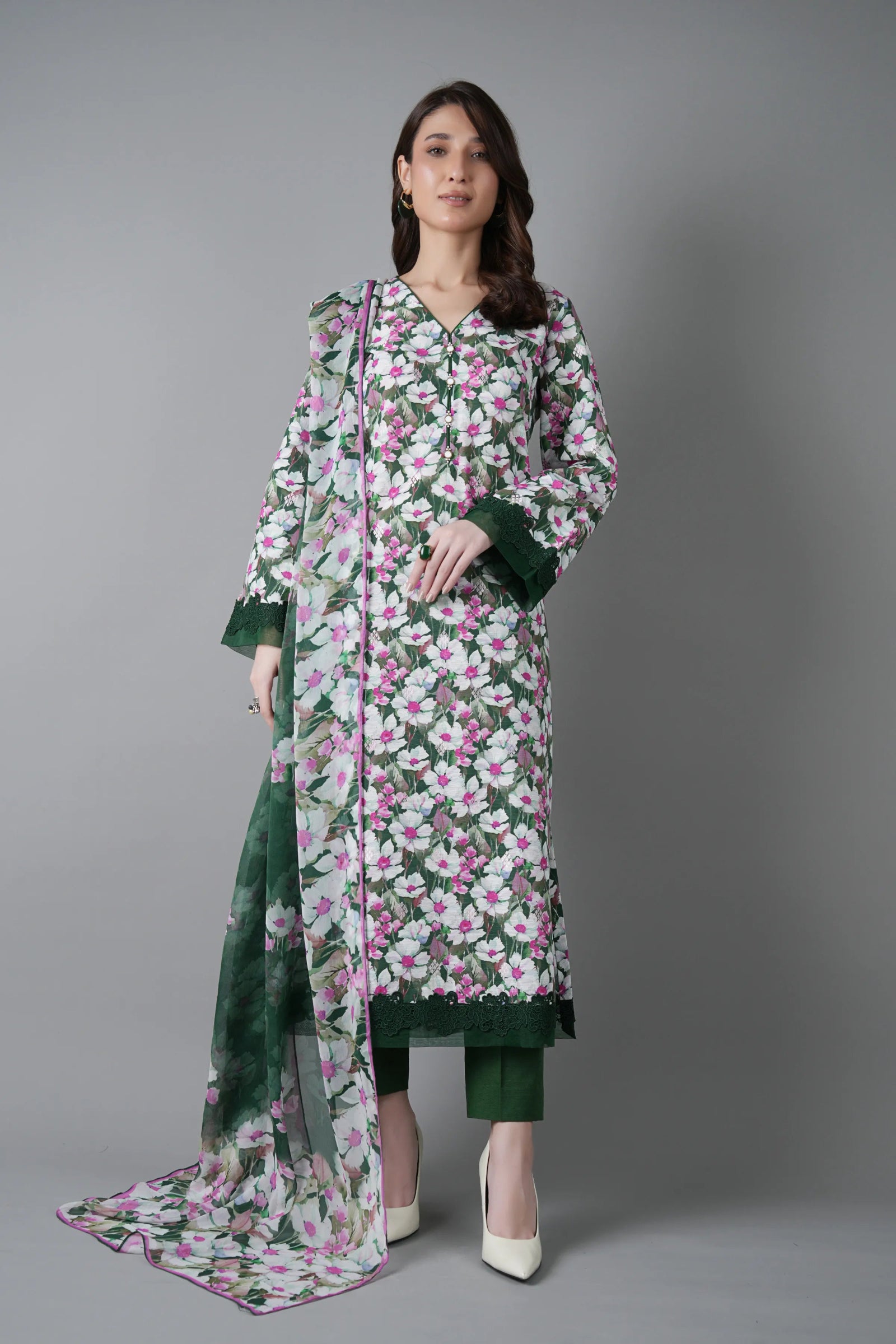 Woman wearing a floral dress with a green dupatta on a gray background
