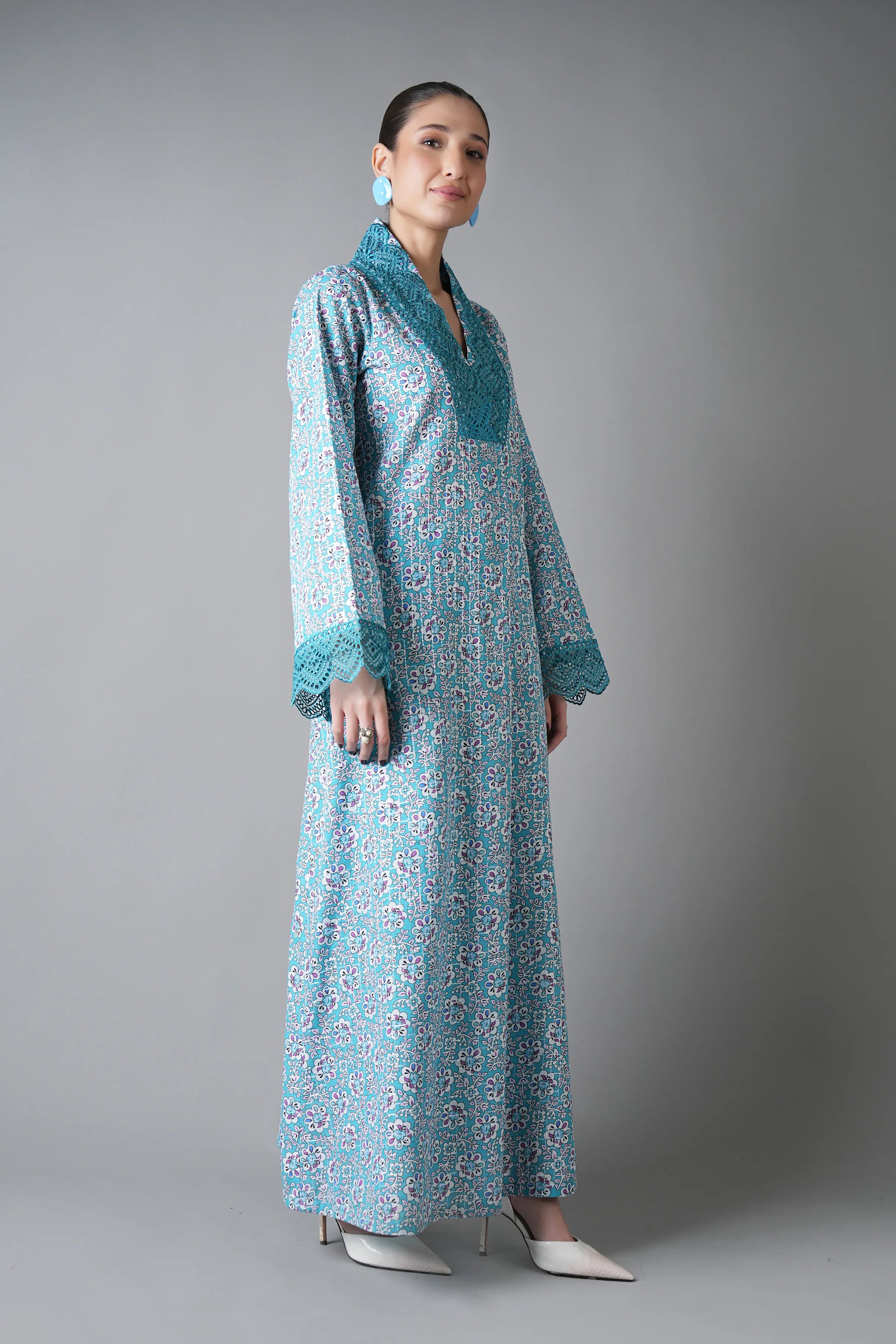 Woman wearing a long, light blue floral dress with a matching jacket against a gray background