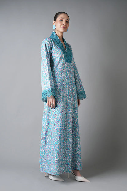 Woman wearing a long, light blue floral dress with a matching jacket against a gray background