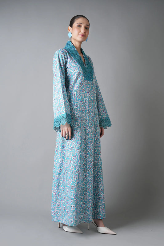 Woman wearing a long, light blue floral dress with a matching jacket against a gray background