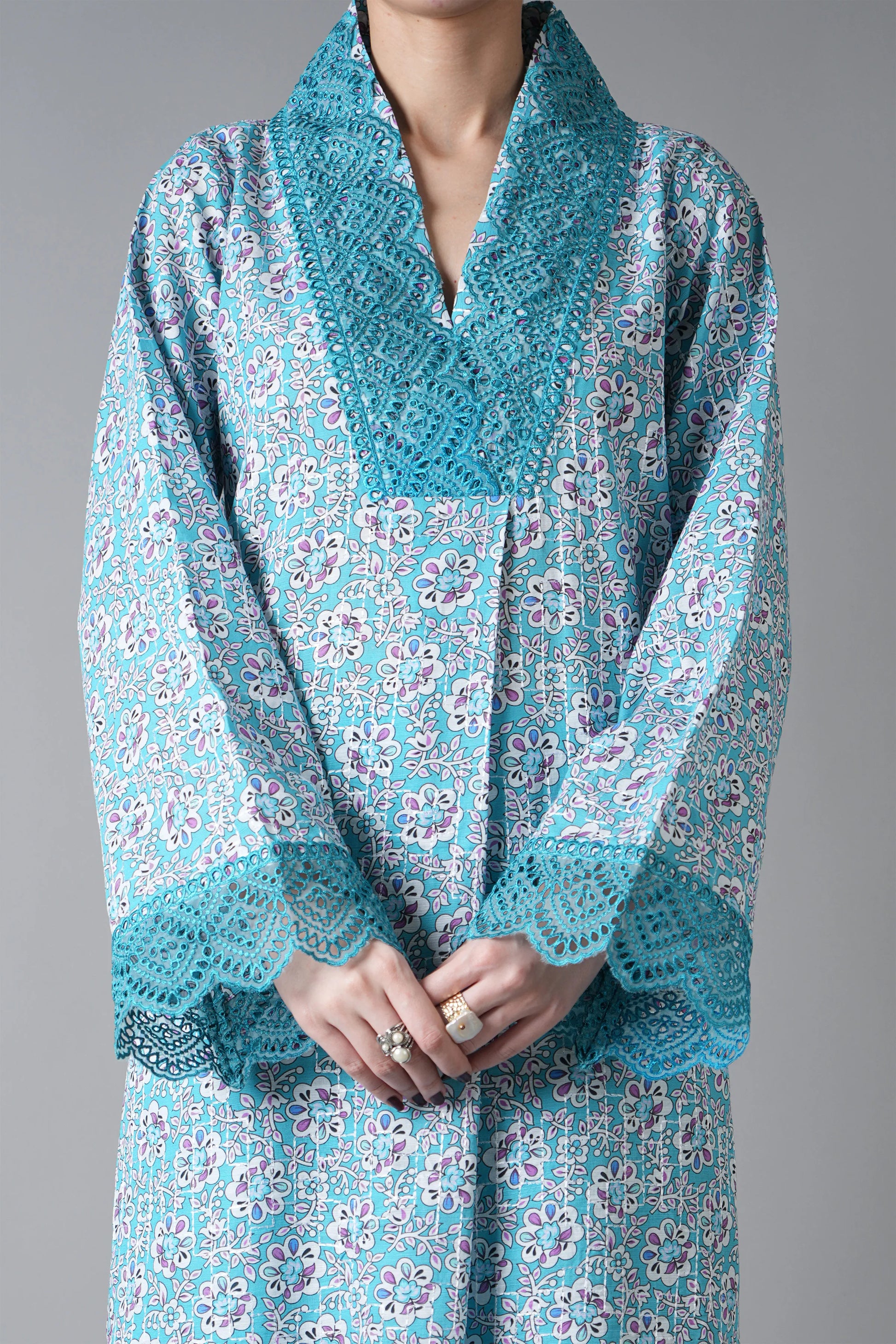 Teal patterned dress with lace details on a gray background