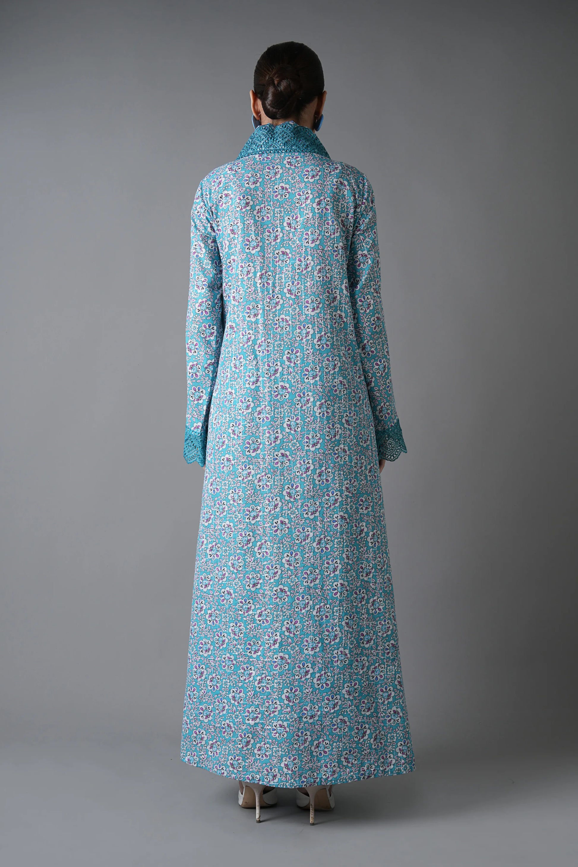 Person wearing a long blue floral dress against a gray background