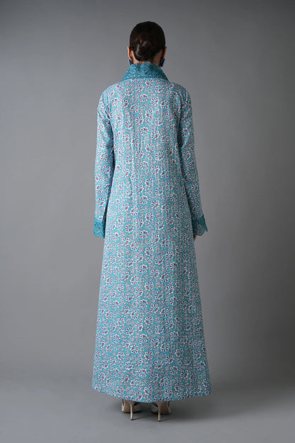 Person wearing a long blue floral dress against a gray background