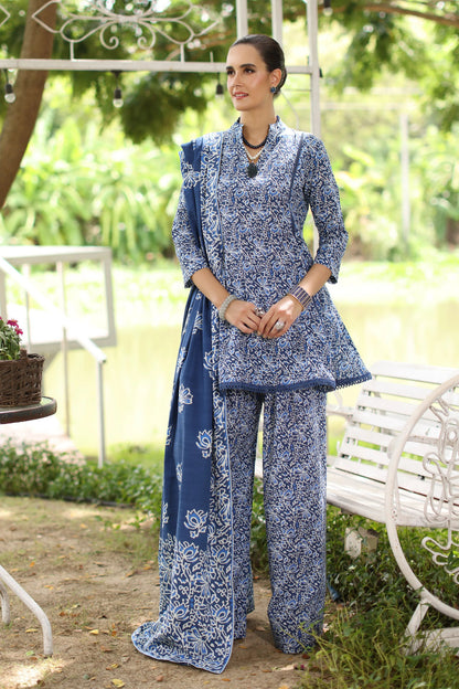 Woman in a blue floral outfit standing in a garden setting