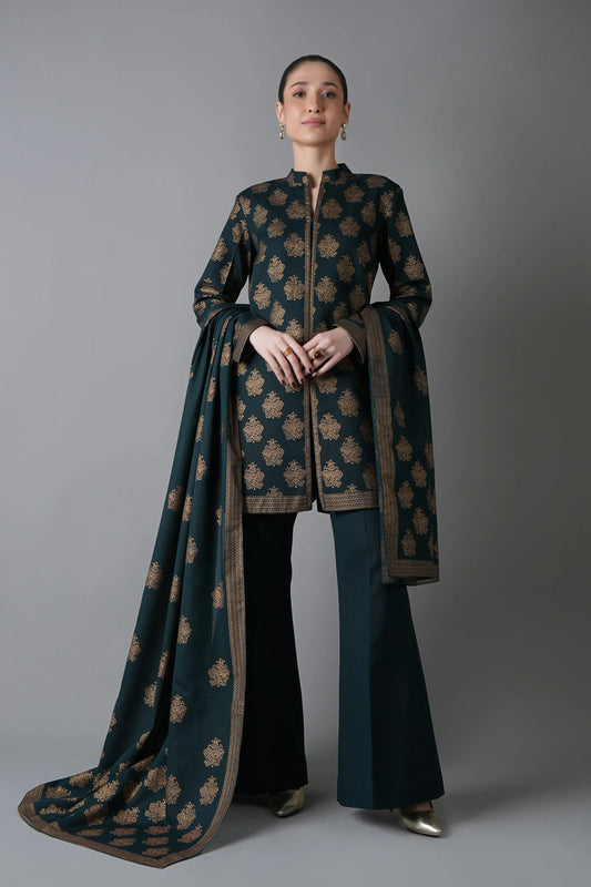 Woman wearing a traditional outfit with a long dark green and brown patterned scarf against a gray background