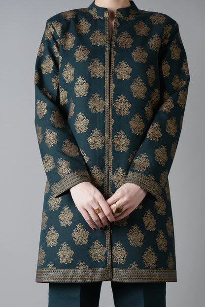 Dark green coat with gold patterns worn by a person on a gray background