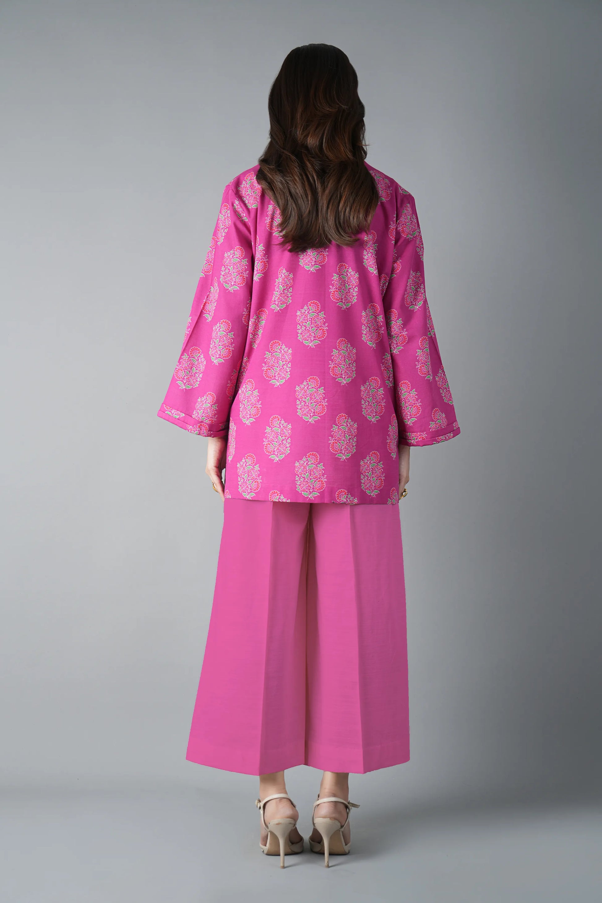 Person wearing a pink outfit with floral patterns on a gray background