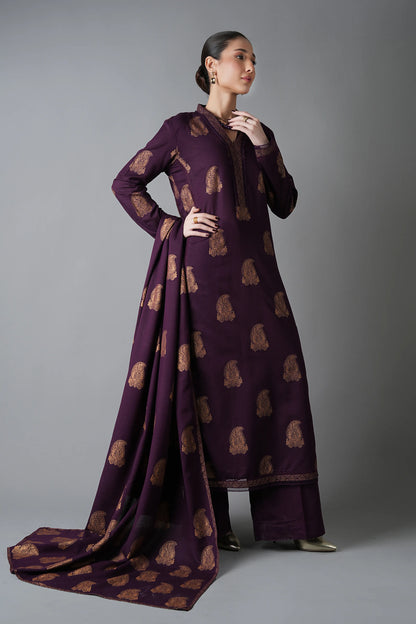 Woman wearing a long, dark purple dress with a pattern on a gray background