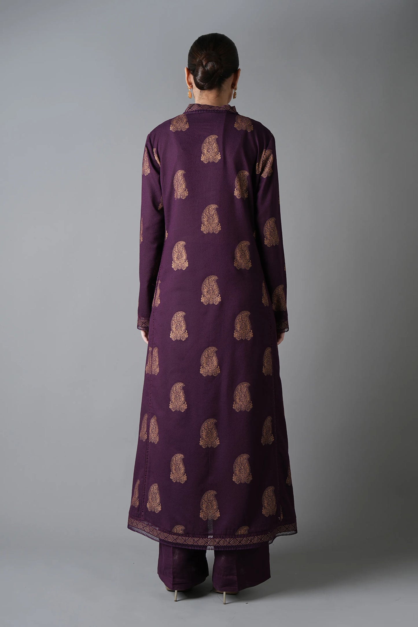 Person wearing a long purple dress with a pattern on a gray background