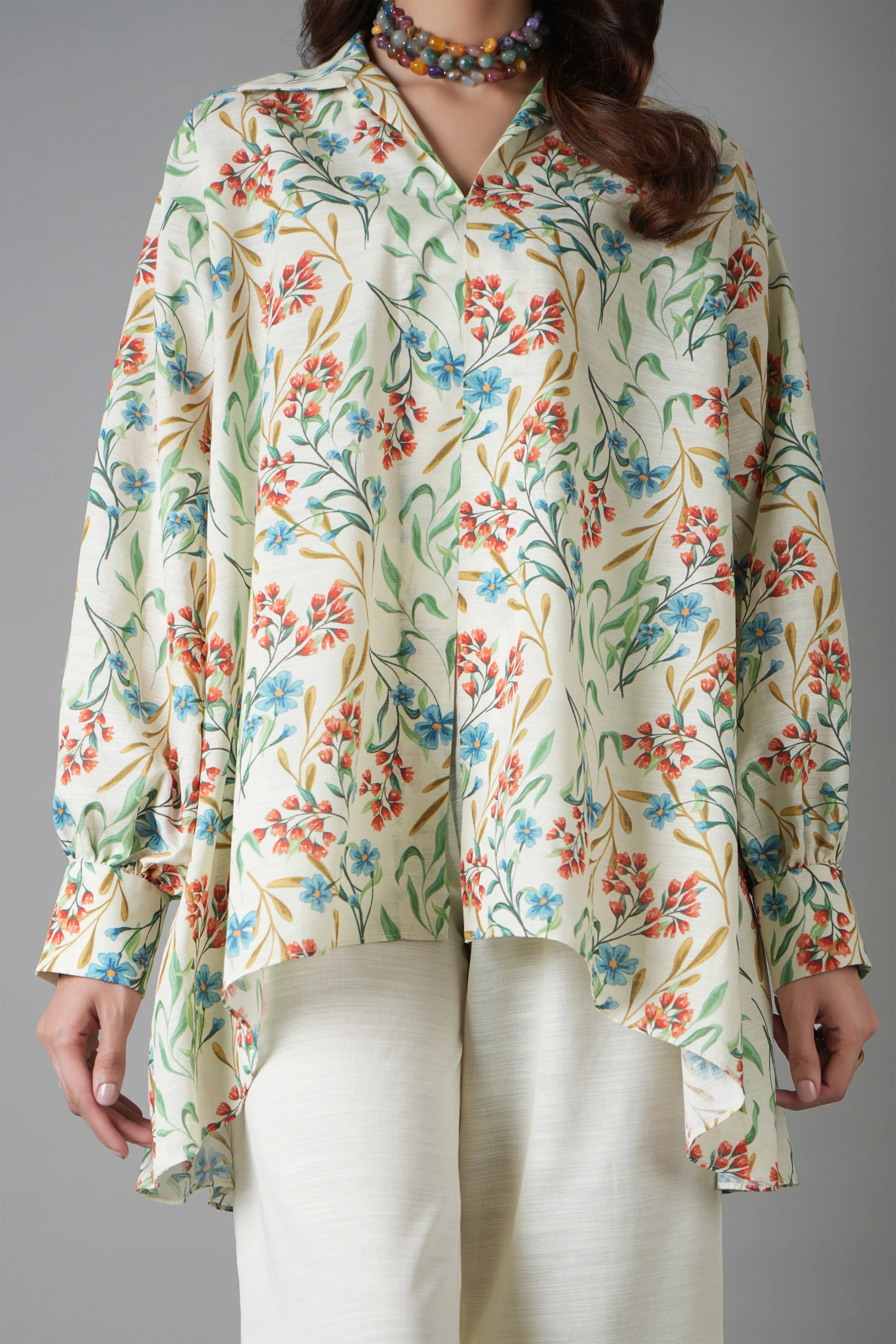 Woman wearing a floral blouse with long sleeves on a gray background