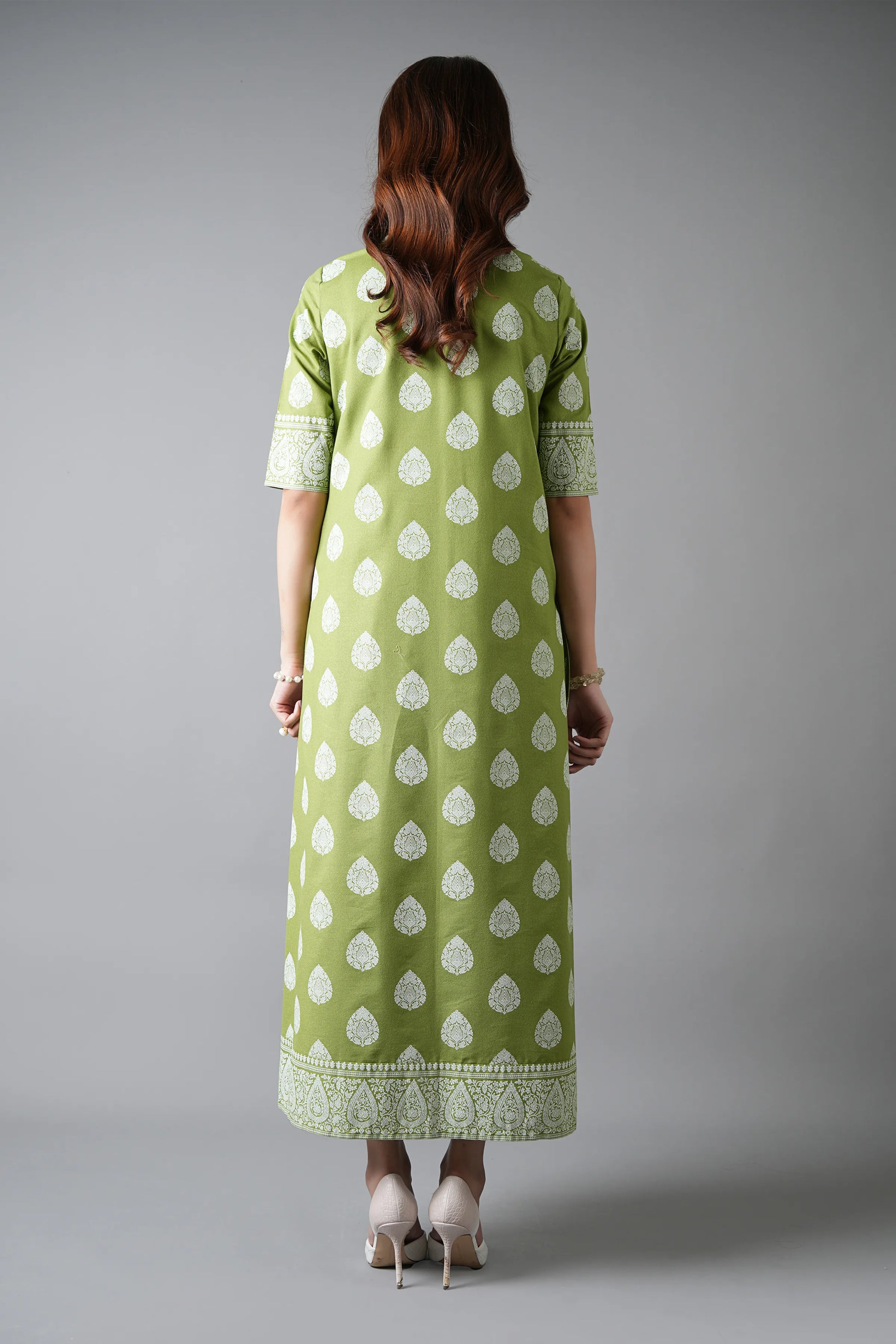 Woman wearing a green dress with white patterns on a gray background
