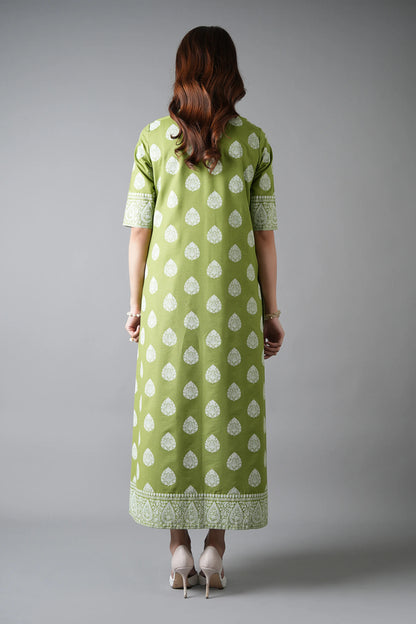 Woman wearing a green dress with white patterns on a gray background