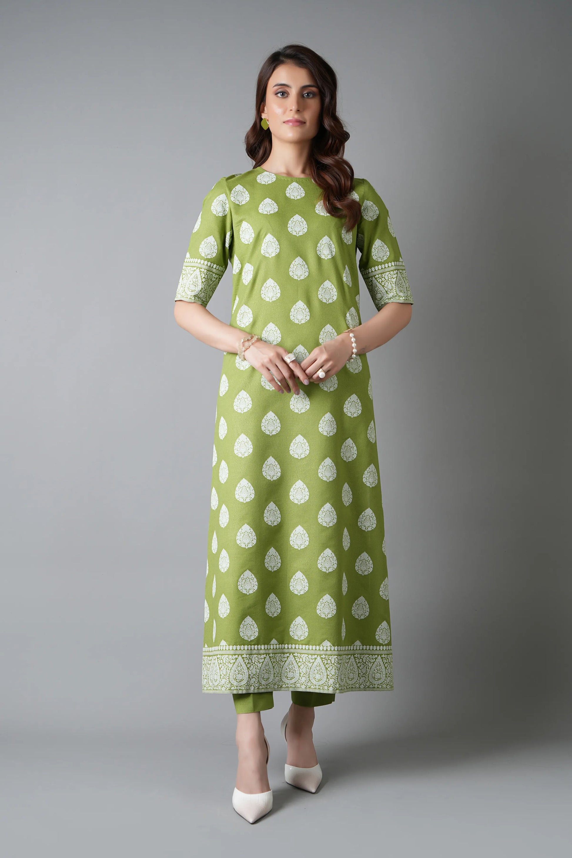 Woman wearing a green and white patterned outfit on a gray background