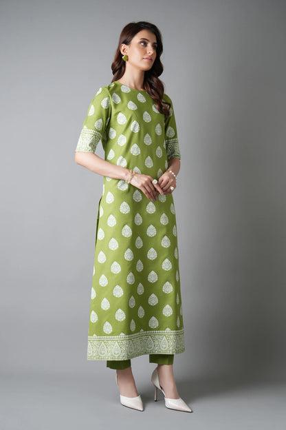 Woman wearing a green dress with white patterns on a gray background