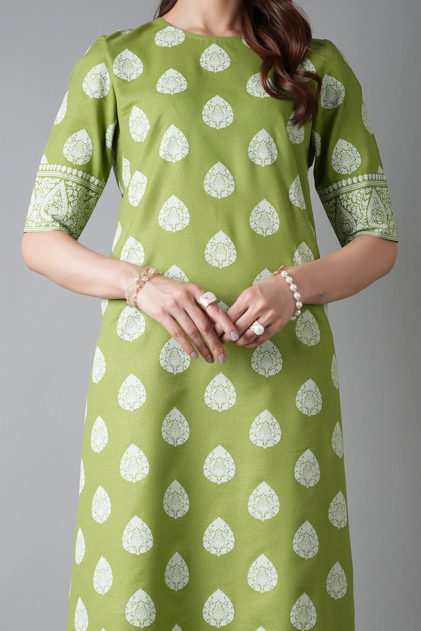 Green dress with white patterns worn by a person on a gray background