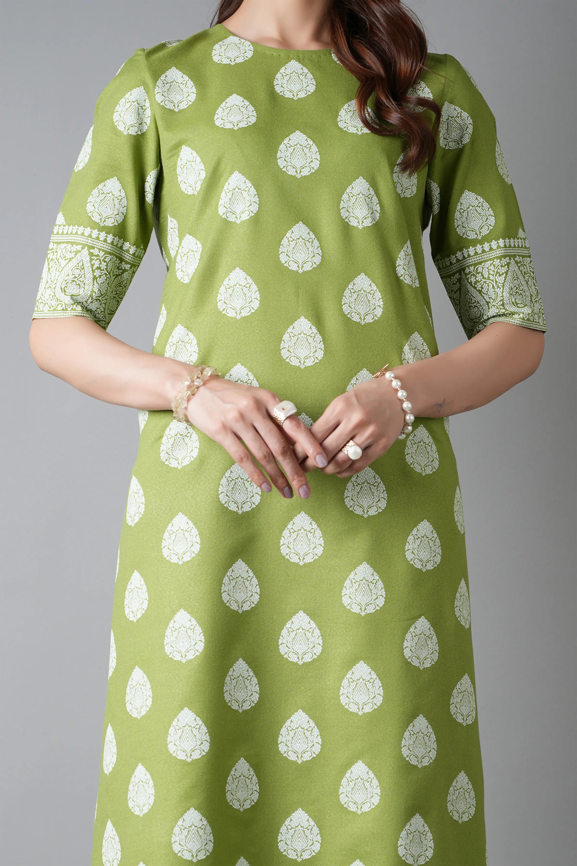 Green dress with white patterns worn by a person on a gray background