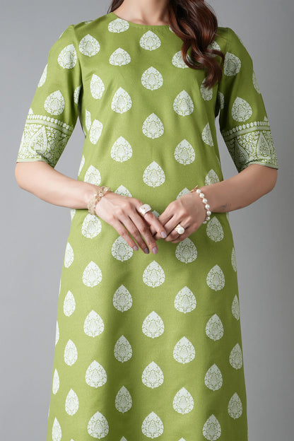 Green dress with white patterns worn by a person on a gray background